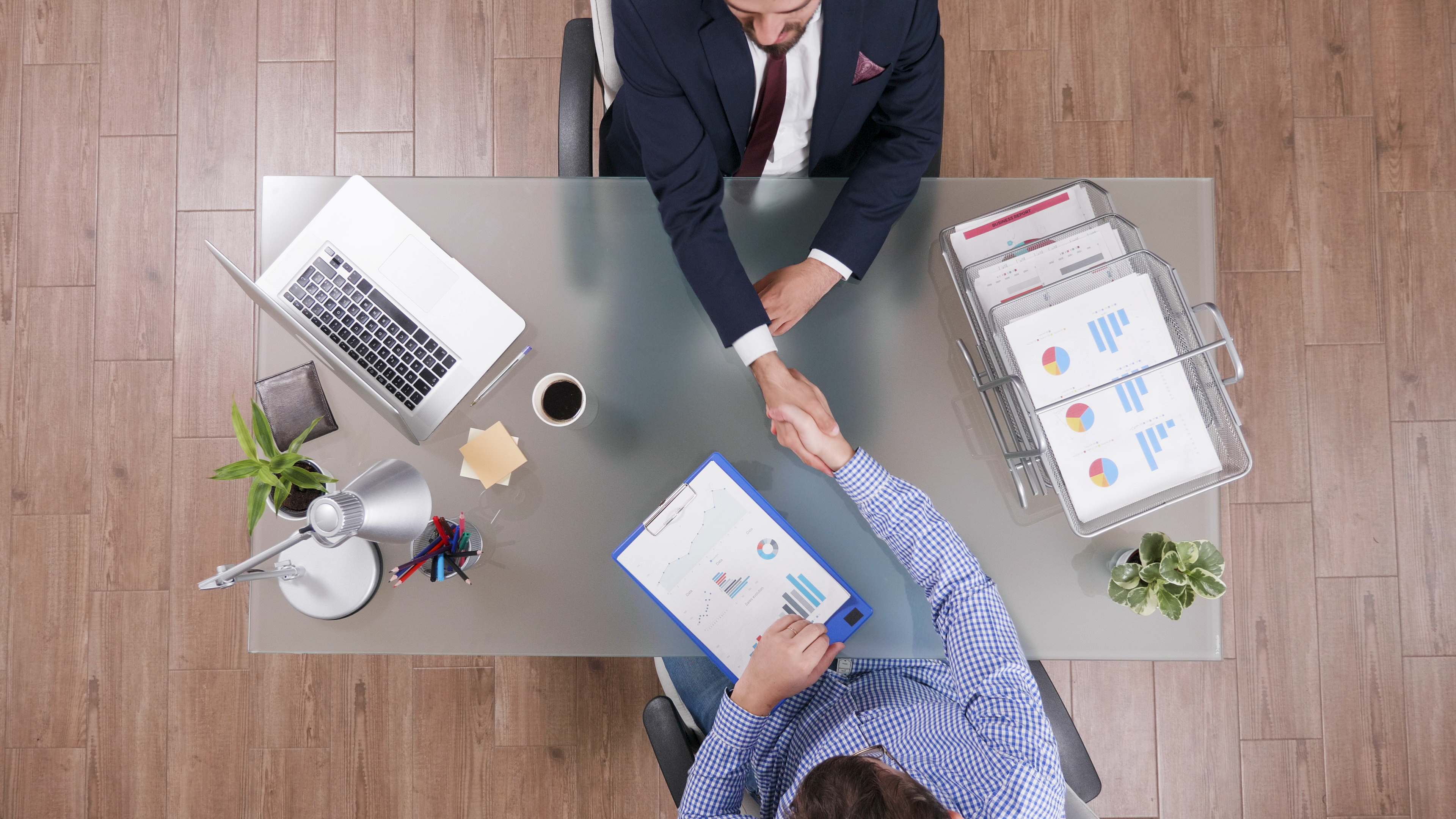 Top view of business meeting handshake at desk.