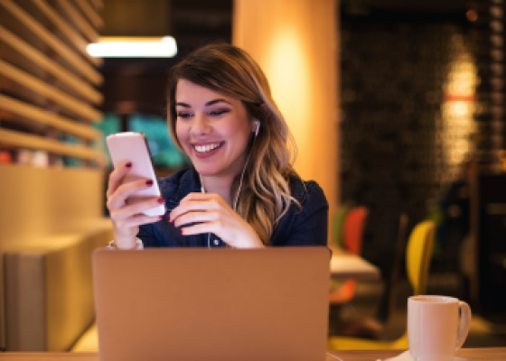 Business woman on phone infront of laptop in cafe