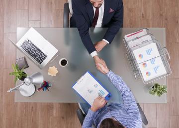Top view of business meeting handshake at desk.