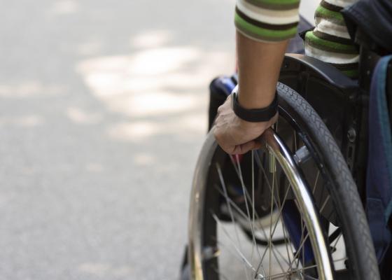 Close up of hand moving wheel of wheelchair.