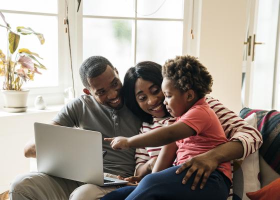 Father, mother and child looking at a laptop.