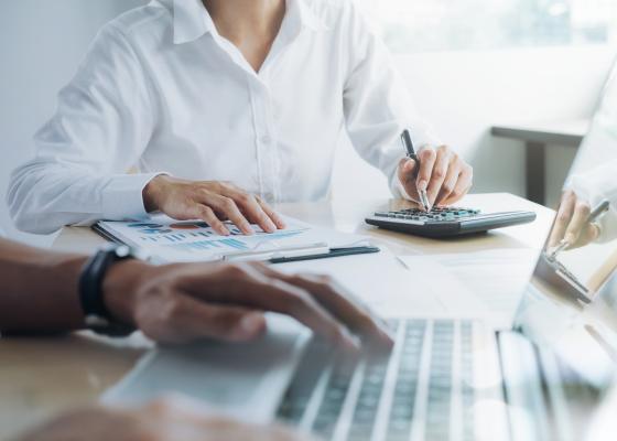 Professional investors working on laptop and calculator.